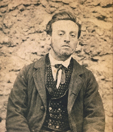 Jean-François Troppmann photographié à Mazas en costume de ville le 9 octobre 1869 par Jules Verrier. Il a été installé devant un des murs en meulière. Il est logé au rez-de-chaussée dans une cellule double 4-6 afin que le gardien puisse être avec lui en permanence. Son procès débutera le 26 décembre. Il sera guillotiné le 19 janvier 1870.